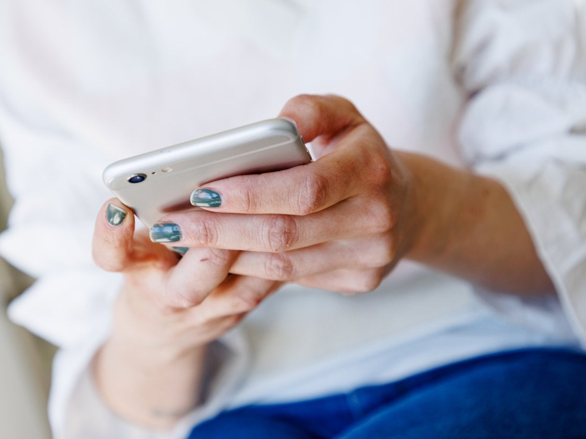 Närbild på händer som håller i en mobiltelefon.