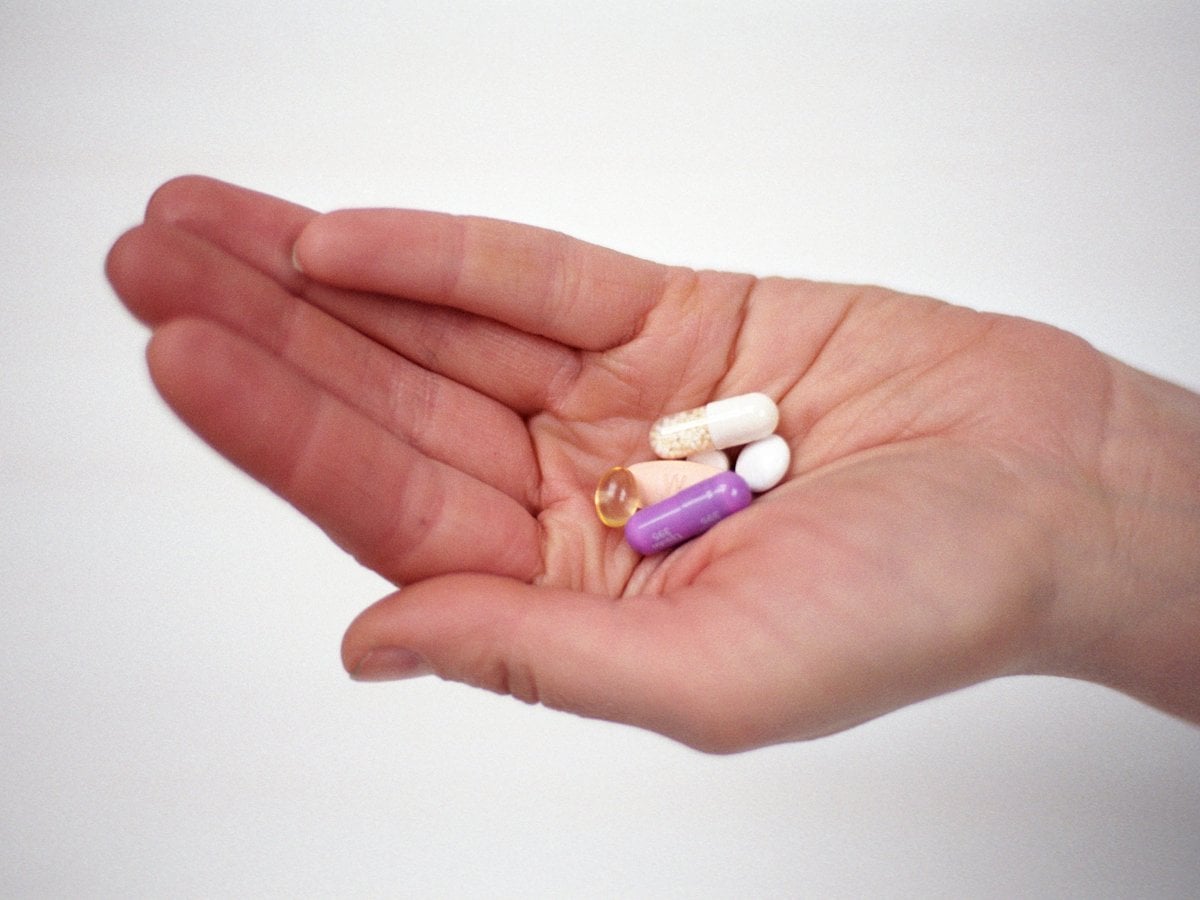 Hand som håller i medicintabletter med olika färger